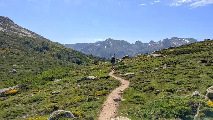 Une randonneuse salue avec ses bâtons sur un sentier de montagne Une randonneuse salue avec ses bâtons sur un sentier de montagne